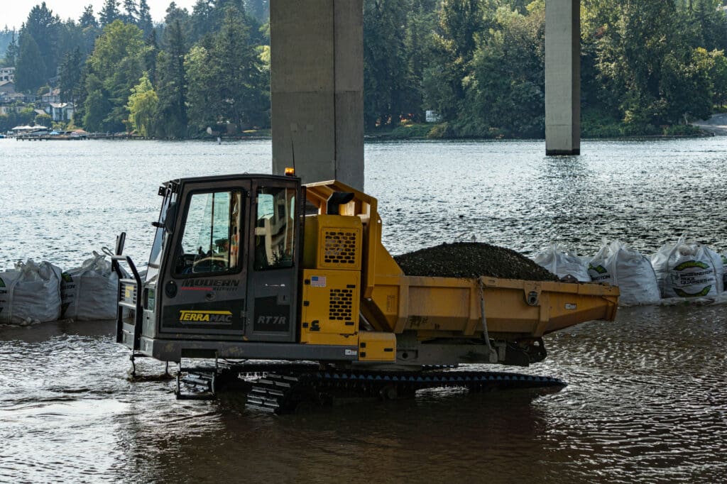 a crawler prepares to dump a load of new streambed sediment into the water along the Bellevue shoreline